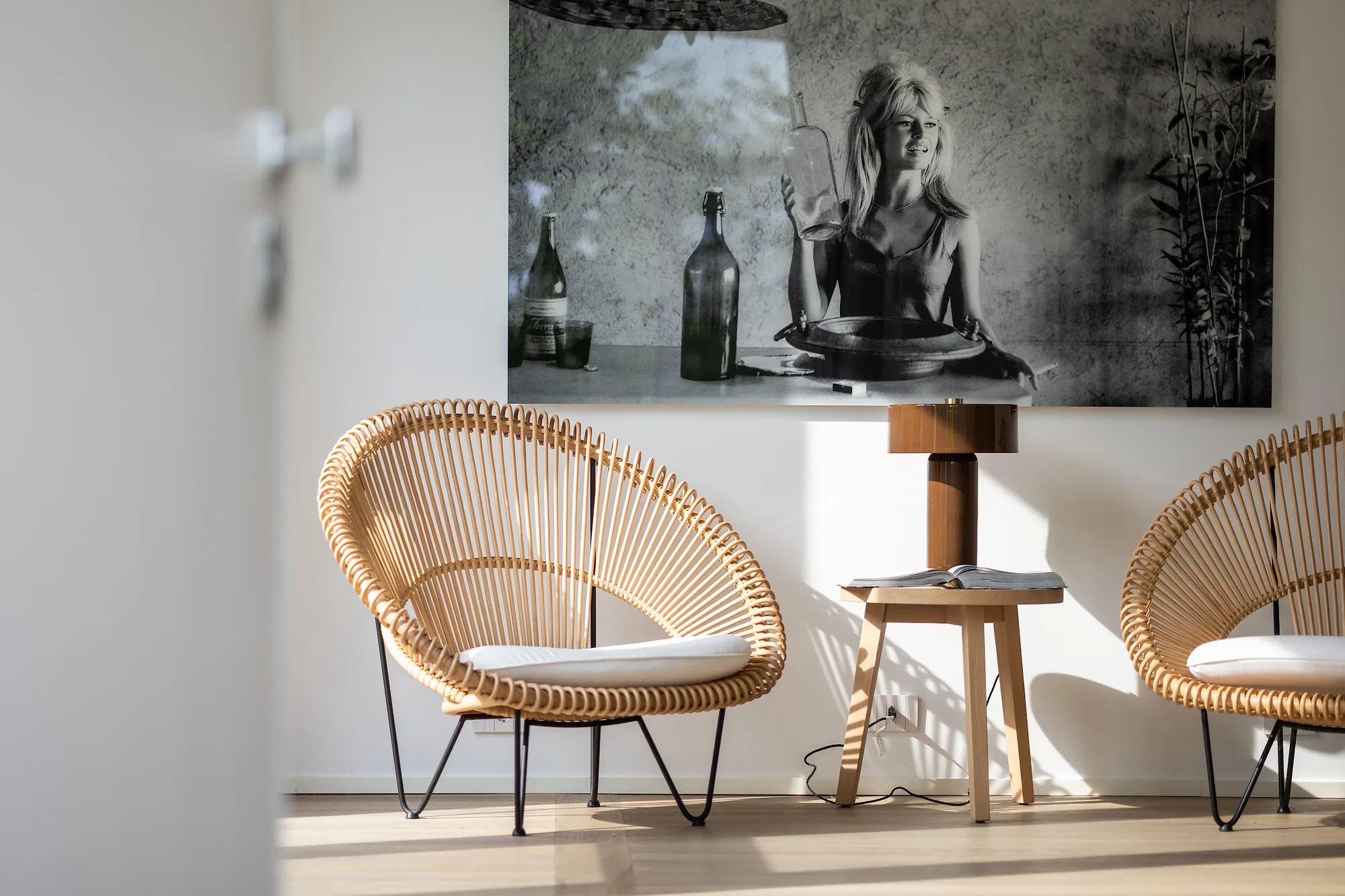 Black-and-white 1960s portrait above two rattan chairs and a wooden side table in the entrance hall